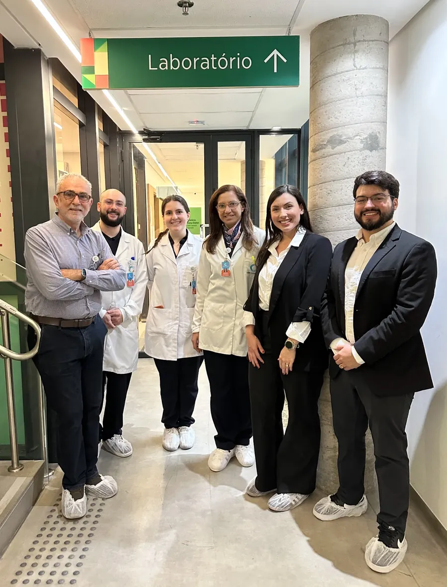 Grupo de visitantes e profissionais da Casa dos Raros diante da entrada do laboratório